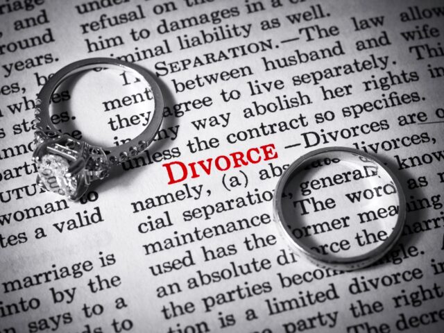 Two rings, one with a large diamond and one plain, placed on a dictionary page open to the word 