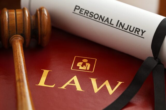 Image of a wooden gavel beside a rolled-up document labeled "Personal Injury," placed on an open red book with the word "LAW" and a small person icon on the cover. The scene represents legal matters, likely regarding personal injury law in Pennsylvania and the statute of limitations involved.
