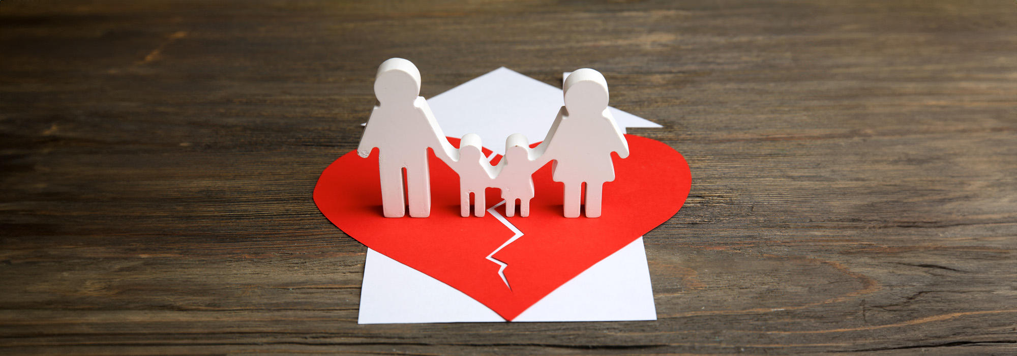 cutout silhouette of a family split apart on a paper heart