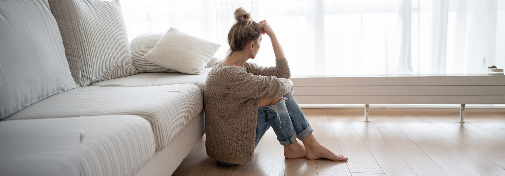 depressed woman is sitting on the floor in the living room