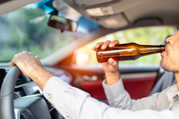 man drinking beer while driving