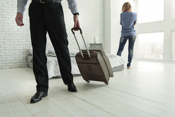 man walking away from woman with suitcase